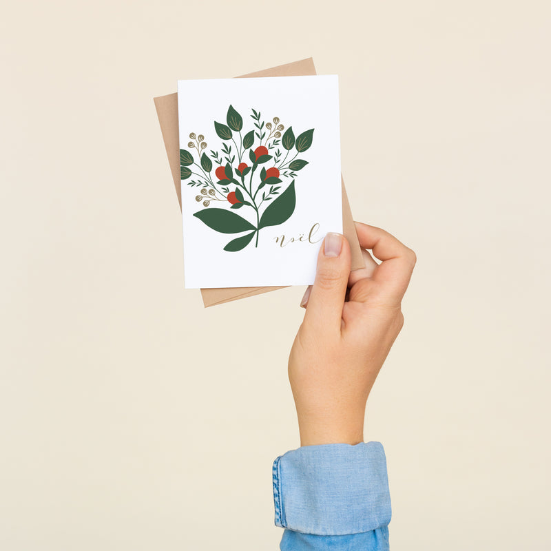 Single folded A2 greeting card with an envelope with an illustration of a winterberry branch and text that states "Noel" in cursive.
