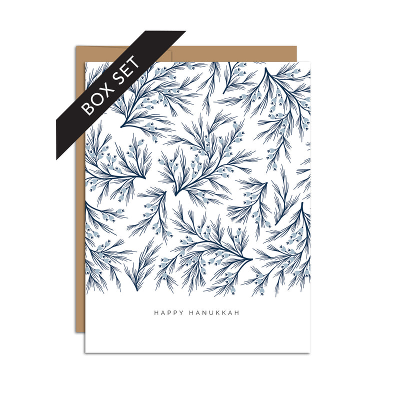 Box set of 8 folded A2 greeting cards with envelopes with an illustration  of dark blue branches and light blue detail. Below this pattern of branches is text that states "Happy Hanukkah".