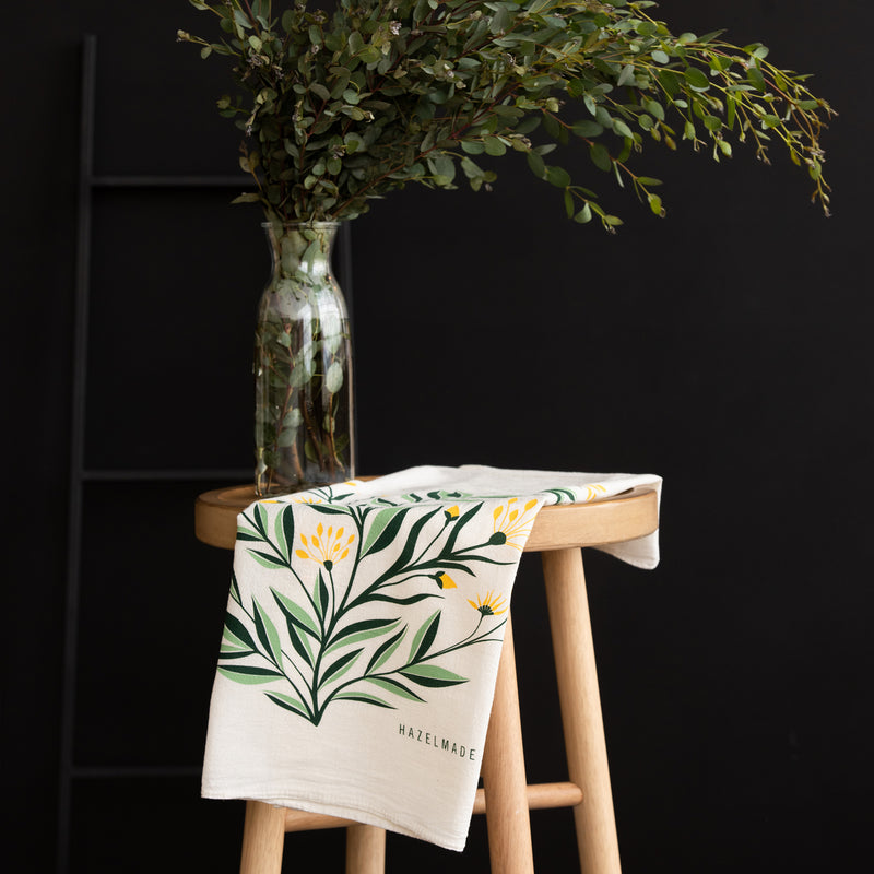 A single 100% cotton flour sack towel with an illustration of a bouquet of yellow flowers
