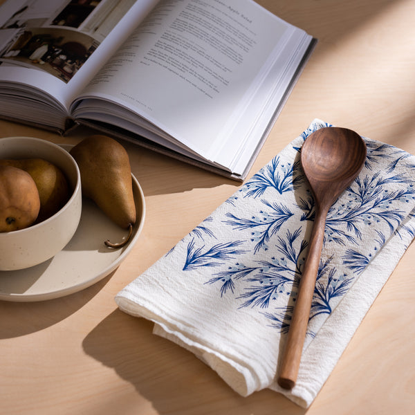 A single 100% cotton flour sack towel with an illustration of blue winter branches