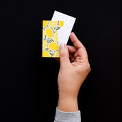 Hand holding a Lemons Mini Note Card with a white envelope against a dark background