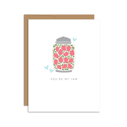 Single folded A2 greeting card with an envelope with an illustration of a jar filled with strawberries and a few blue hearts surrounding the jar. Directly below the jar is text that states "You're My Jam".