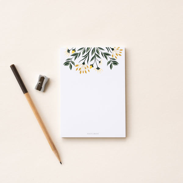 A single 4” by 5.5” small notepad with 50 tear-off sheets and an illustration of yellow flowers and green leaves sprouting from the top of the notepad while the rest is blank.