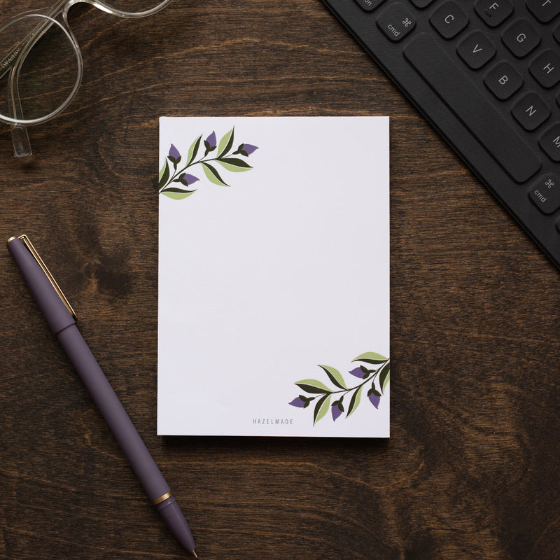 A single 4” by 5.5” small notepad with 50 tear-off sheets and an illustration of purple ivy sprigs in the top left and bottom right corners. The rest is blank.