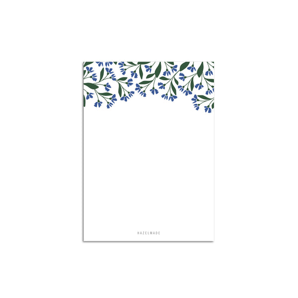A single 4” by 5.5” small notepad with 50 tear-off sheets and an illustration of small blue flowers and green leaves wrapping the top of the notepad and the rest being blank.