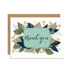 Single folded A2 greeting card with an envelope with an illustration of text stating "Thank You" in cursive bordered by a blue background and leaves sprouting behind it.