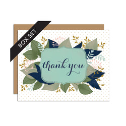 Box set of 8 folded A2 greeting cards with envelopes with an illustration    of text stating "Thank You" in cursive bordered by a blue background and leaves sprouting behind it.