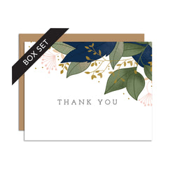 Box set of 8 folded A2 greeting cards with envelopes with an illustration   of blue and green leaves sprouting from the top right corner of the card. In the center is text that states "Thank You".