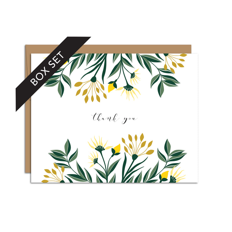 Box set of 8 folded A2 greeting cards with envelopes with an illustration  of yellow aster flowers and green leaves sprouting from the top and bottom of the card. In the center is text in cursive that states "Thank You".