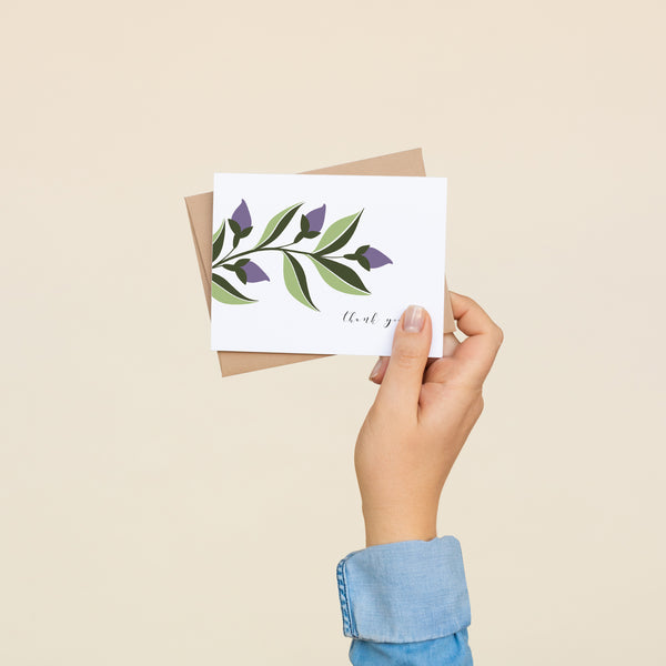 Single folded A2 greeting card with an envelope with an illustration of purple ivy and green leaves sprouting from the left side of the card. In the bottom right is text in cursive that states "Thank You".