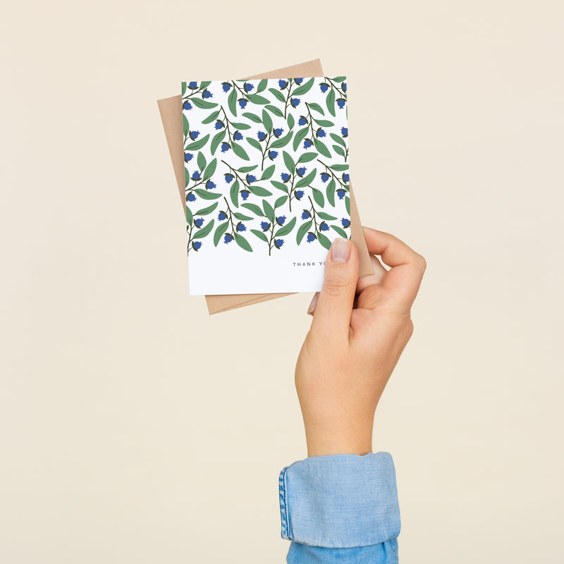 Box set of 8 folded A2 greeting cards with envelopes with an illustration   of blueberries and green leaves pattern. In the bottom right is text that states "Thank You".