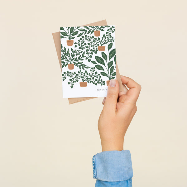 Single folded A2 greeting card with an envelope with an illustration of multiple houseplants in pots. In the bottom right corner is text that states "Thank You".