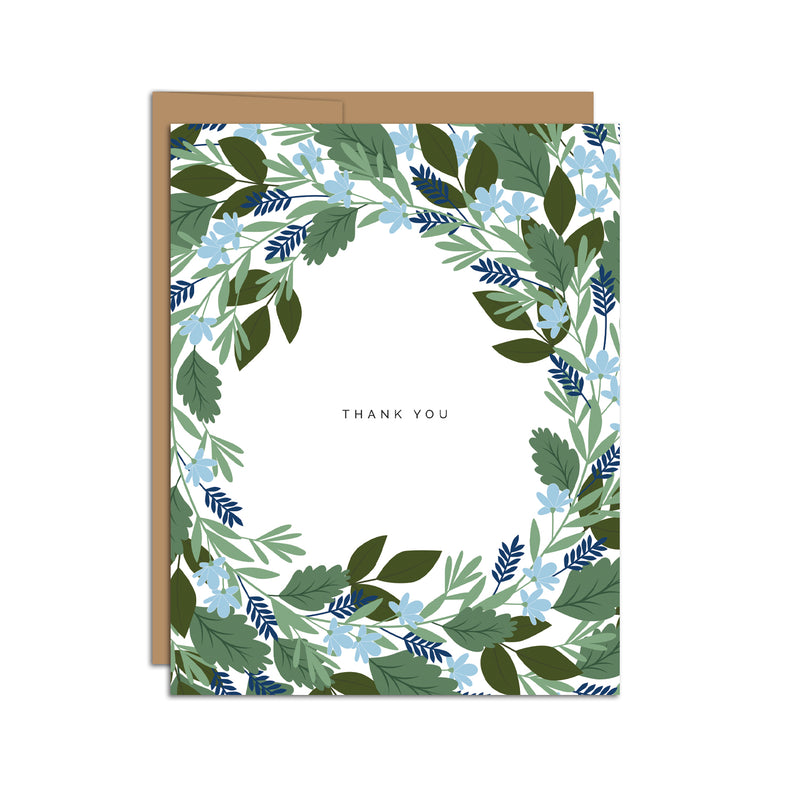 Single folded A2 greeting card with an envelope with an illustration of blue flowers and green leaves circling/bordering all edges of the card. In the center is text that states "Thank You".