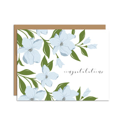 Single folded A2 greeting card with an envelope with an illustration of blue dogwood flowers wrapping the top, bottom, and left side of the card. On the right side is text that states "Congratulations".