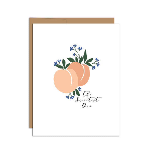 Single folded A2 greeting card with an envelope with an illustration of two peaches in the center of the card with small blue flowers blooming around them. Below the peaches states "The Sweetest Duo".